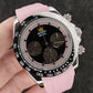 Watch with pink strap held in a hand against a dark textured background